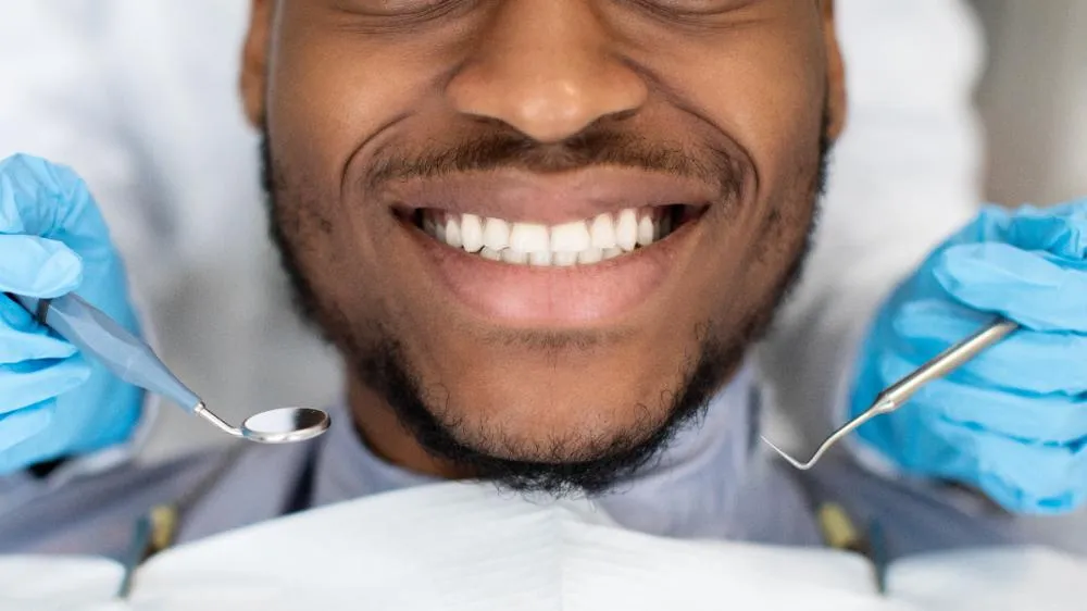 smiling black male patient getting treatment at the dentist