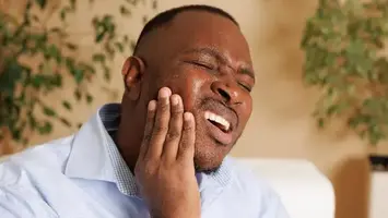 Man holding his cheek in dental pain